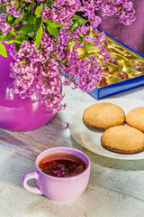 Composition with cup, cookies and lilacs in a vase