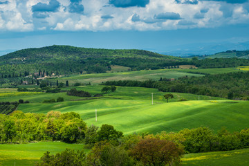 Fototapeta na wymiar Tuscany spring, rolling hills and windmill on sunset. Rural landscape. Green fields. Italy, Europe