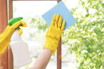 Girl housewife washes the windows in the house in yellow rubber gloves and with a blue rag....