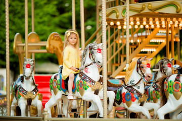 Adorable little girl near the carousel outdoors in Paris, baby girl on the carousel, Happy healthy baby child having fun outdoors on sunny day. Family weekend or vacations © Tina kids photo
