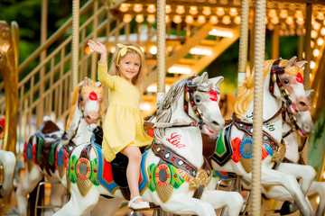 Adorable little girl near the carousel outdoors in Paris, baby girl on the carousel, Happy healthy...