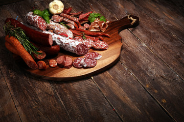 Food tray with cold meat with delicious salami and herbs . Variety of meat products including coppa and sausages