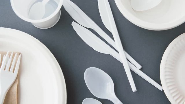 eating, recycling and ecology concept - disposable plastic dishes on grey background