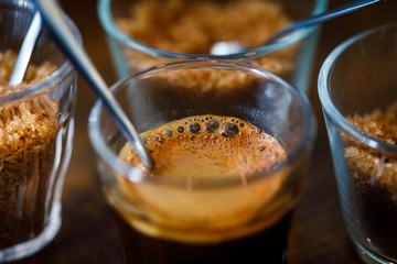 coffee in glass cup with metal spoon and sugar