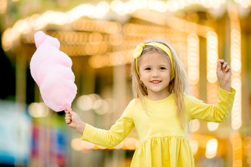 happy child girl with cotton candy at an amusement Park. the concept of the international...