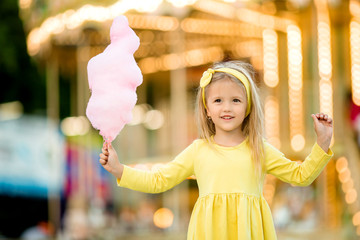 happy child girl with cotton candy at an amusement Park. the concept of the international...