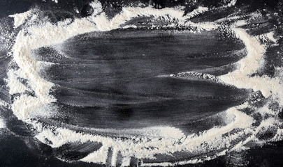 white wheat flour scattered on a black table