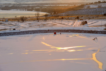 Sunset Icy Lake - A few people are ice-fishing on a frozen lake at Chatfield State Park on a very cold Winter evening. Denver-Littleton, Colorado, USA.