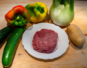 Ground raw meat in white dish, with vegetables