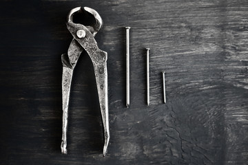 tongs, antique forged woodworking tools for removing nails from wooden structures, on a dark wooden...