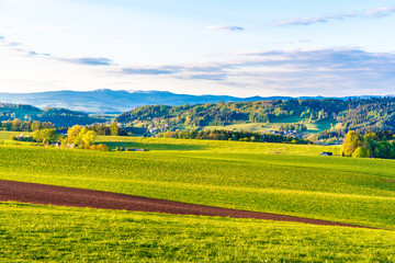 Fototapeta na wymiar Green hilly landscape with Giant Mountains, Czech: Krkonose, on skyline, Czech Republic.