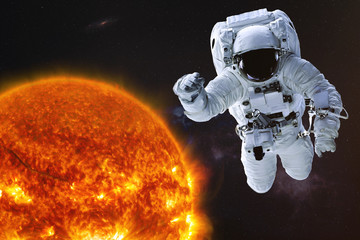 Fototapeta na wymiar Astronaut in outer space with Sun of solar system. Science fiction wallpaper. Elements of this image were furnished by NASA.
