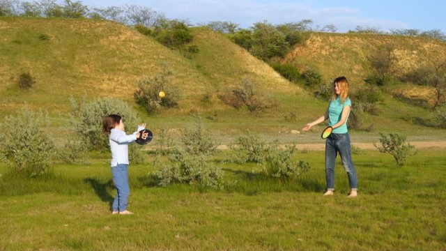 happy family in nature, mom and son throw a ball, run barefoot, father kritit son by the hands, the family enjoys the sunset