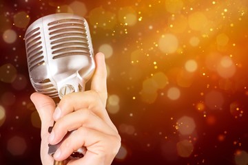 Female hand holding a single retro microphone - isolated image
