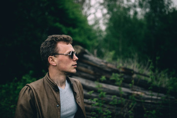 trendy A man in a brown leather jacket and in steampunk glasses in the forest.