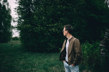 trendy A man in a brown leather jacket and in steampunk glasses in the forest.