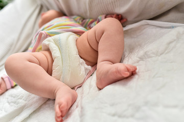 Newborn baby laying on a sofa with disposable diapers ready to change.