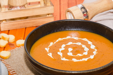 Homemade fresh pumpkin cream soup served with croutons on a rustic background