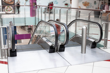 View of escalator in shopping center. Retail concept. Led lighting in mall. Customers and shoppers...