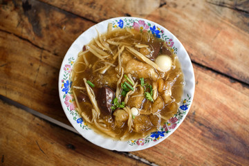 Chinese  Fish maw with red gravy soup in bowl on wooden table
