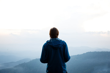 Silhouette of a man with mountains layer background during in the sunset sky