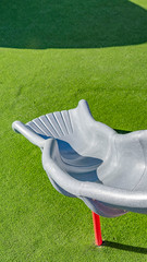 Vertical Shiny gray slide of a playground viewed against a vibrant green lawn