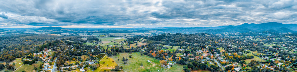 Wide aerial panorama of scenic rural landscape with houses surrounded by forest and mountains. Healesville, Victoria, Australia