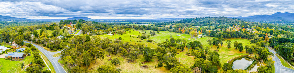 Wide aerial panoramic landscape of scenic countryside. Grasslands among trees and mountains in Australia