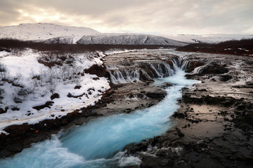 Beautiful scenery of Bruarfoss waterfall at southern Iceland where a series of small runlets of water runs into a beautiful, turquoise-blue colored pool. Travel and natural Concept.