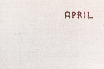 The word April written with coffee beans shot from above, aligned at the top right.