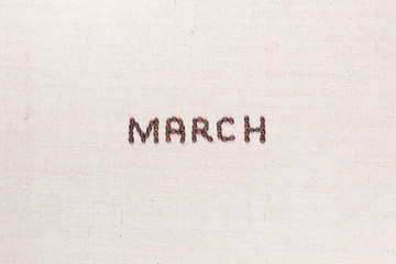 The word March written with coffee beans shot from above, aligned in the center.
