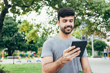 Young man reading e-book in the park