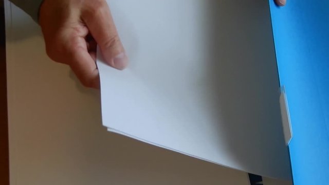 Hands are placing papers in a folder .