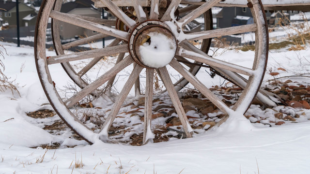Clear Panorama Rusty wheel of a wooden cart against a rocky ground covered with snow in winter