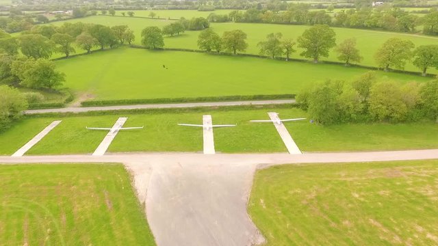 rising view of several parked hand gliders beside runway