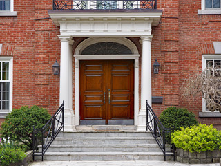 elegant double wooden front door of large suburban house with portico