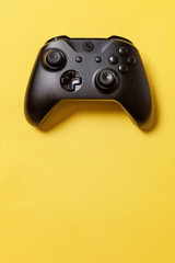 Black joystick gamepad, game console on yellow colourful trendy modern fashion pin-up background. Computer gaming competition videogame control confrontation concept. Cyberspace symbol