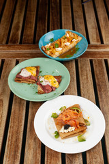Different kinds of thin pancakes or blini with pineapple and caramel sauce, smoked salmon and caviar, poached egg and bacon
