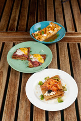 Crepes with pineapple and caramel sauce, smoked salmon and caviar, poached egg and bacon on a wooden rustic table