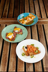 Different kinds of thin pancakes or blini with pineapple and caramel sauce, smoked salmon and caviar, poached egg and bacon