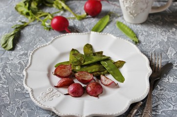 Fried young peas and radish pods. In the style of Provence. light background. Soft focus