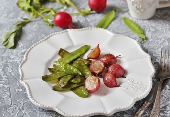 Fried young peas and radish pods. In the style of Provence. light background. Soft focus