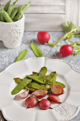 Fried young peas and radish pods. In the style of Provence. light background. Soft focus