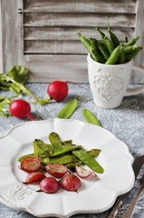 Fried young peas and radish pods. In the style of Provence. light background. Soft focus