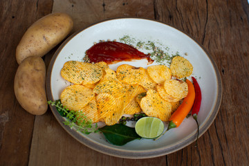 Crispy potato chips snack On the plate, placed on the old wooden floor and potato head