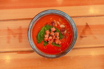 Top view of seasonal vegetarian gazpacho with herbs and tomatoes on wooden table