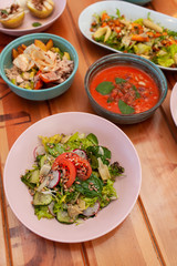 Side view of poke bowl, gazpacho, vegetable salads, BBQ fruits and vegan noodle soup