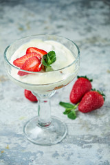 Ice cream with strawberries in a glass vase. Gray textured background. Dessert