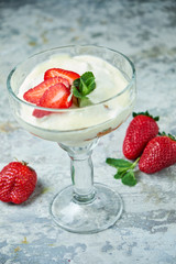 Ice cream with strawberries in a glass vase. Gray textured background. Dessert