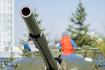 In the city Park children visiting and playing on the tower of a military tank